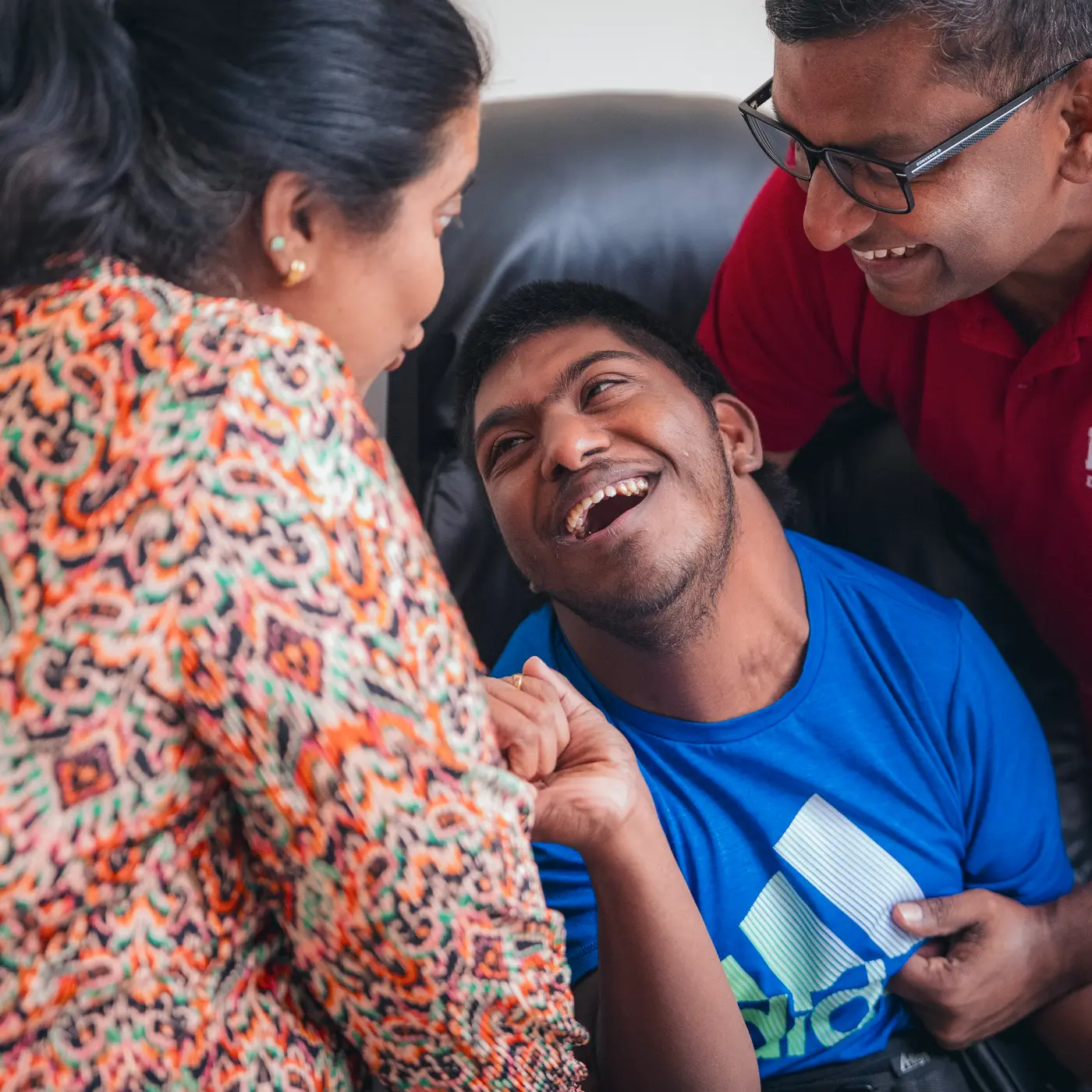 Daina and Bejoy leaning in towards their son, all three laughing